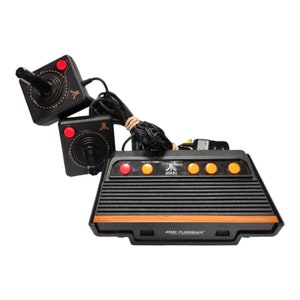 May include: A black Atari Flashback 8 console with two black and red joystick controllers. The console has a black and orange design with the Atari logo and the text "ATARI FLASHBACK" printed on the front.