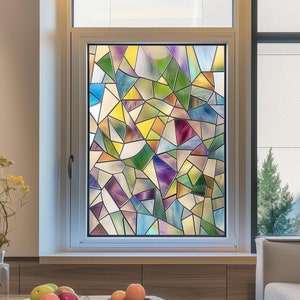 May include: A window with a colorful stained glass design featuring geometric shapes in shades of blue, green, yellow, and purple. The window is framed in white and set against a light brown wall.