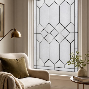 Op de afbeelding: Een raamfolie met een geometrisch patroon van dunne zwarte lijnen die langwerpige zeshoeken en ruitvormen vormen tegen een matte, halfdoorzichtige witte achtergrond. Het ontwerp creëert een rasterstructuur over het hele glas.