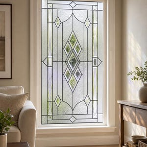 Op de afbeelding: Een rechthoekig raam met decoratief glas-in-lood met een geometrisch patroon. Het ontwerp bevat heldere glaspanelen omringd door gestructureerde, matglazen secties die in ruitvormen en verticale lijnen in een wit kozijn zijn geplaatst.