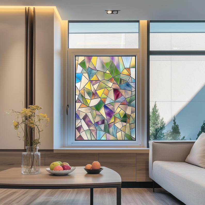 May include: A window with a colorful stained glass design featuring geometric shapes in shades of blue, green, yellow, and purple. The window is framed in white and set against a light brown wall.