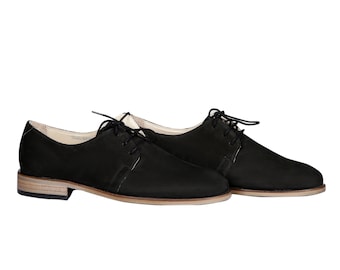 May include: A pair of black leather lace-up shoes with a low heel and a rounded toe.