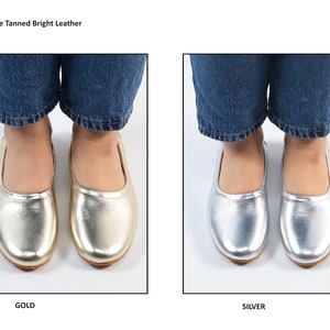Puede incluir: Dos pares de bailarinas de cuero dorado y plateado. Los zapatos se muestran en una modelo que lleva pantalones vaqueros azules. El texto "Vegetable Tanned Bright Leather" est&aacute; en la parte superior de la imagen. El texto "GOLD" est&aacute; debajo de los zapatos dorados y el texto "SILVER" est&aacute; debajo de los zapatos plateados.