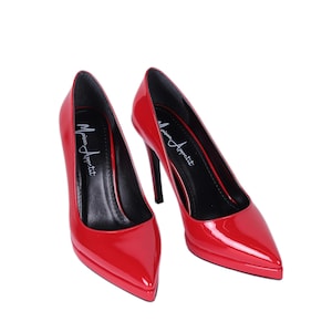 May include: Pair of glossy red high heels with pointed toes and stiletto heels. The shoes have the text "Maison Appetit" printed on the insole. The heels are a classic style, suitable for formal occasions.