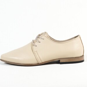 May include: A pair of cream-colored leather lace-up shoes with a pointed toe and a low heel.