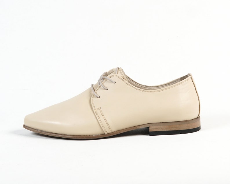 May include: A pair of cream-colored leather lace-up shoes with a pointed toe and a low heel.