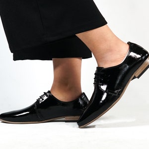 May include: A pair of black patent leather lace-up shoes with a pointed toe and a low heel.
