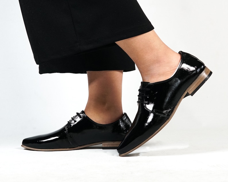 May include: A pair of black patent leather lace-up shoes with a pointed toe and a low heel.