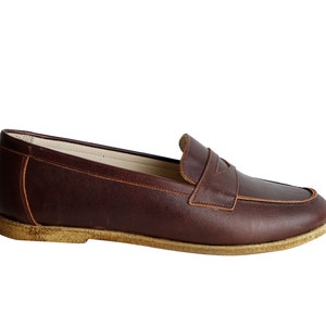 May include: A pair of brown leather loafers with a suede sole.
