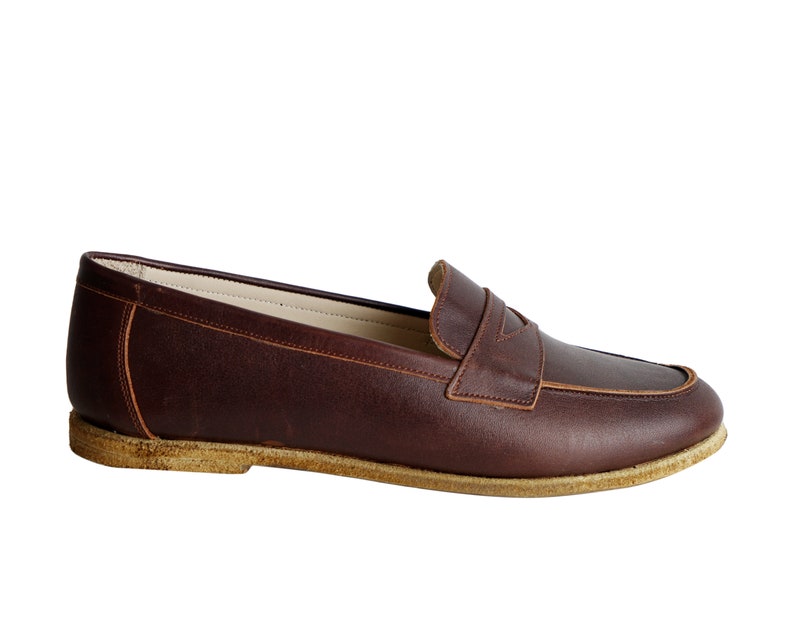 May include: A pair of brown leather loafers with a suede sole.