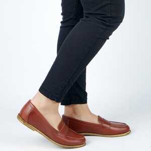 May include: A pair of brown leather loafers with a simple design. The loafers have a rounded toe and a low heel.