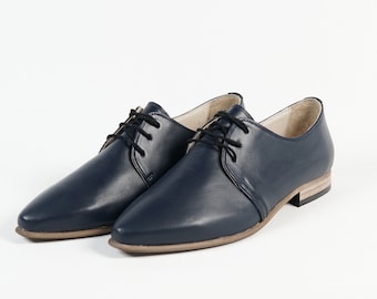 May include: A pair of navy blue leather lace-up shoes with a pointed toe and a low heel.
