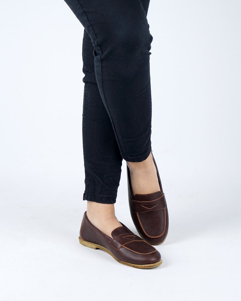 May include: A pair of brown leather loafers with a tassel detail. The loafers are worn with black pants.