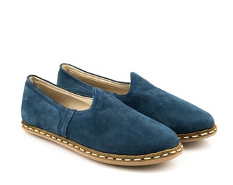 May include: A pair of blue suede slip-on shoes with a brown and white stitched sole.