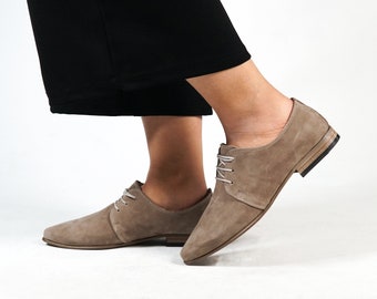 May include: A pair of light brown suede lace-up shoes with a pointed toe and a low heel.