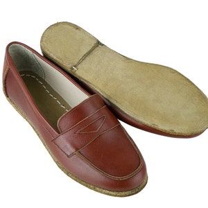 May include: A pair of brown leather loafers with a stitched detail on the front. The loafers have a leather sole and a slightly rounded toe.