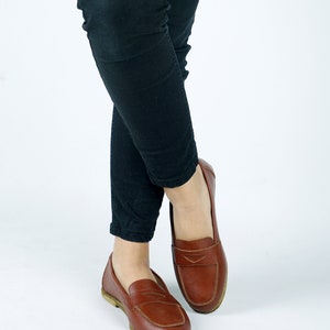 May include: A pair of brown leather loafers with a simple design. The loafers have a pointed toe and a low heel.