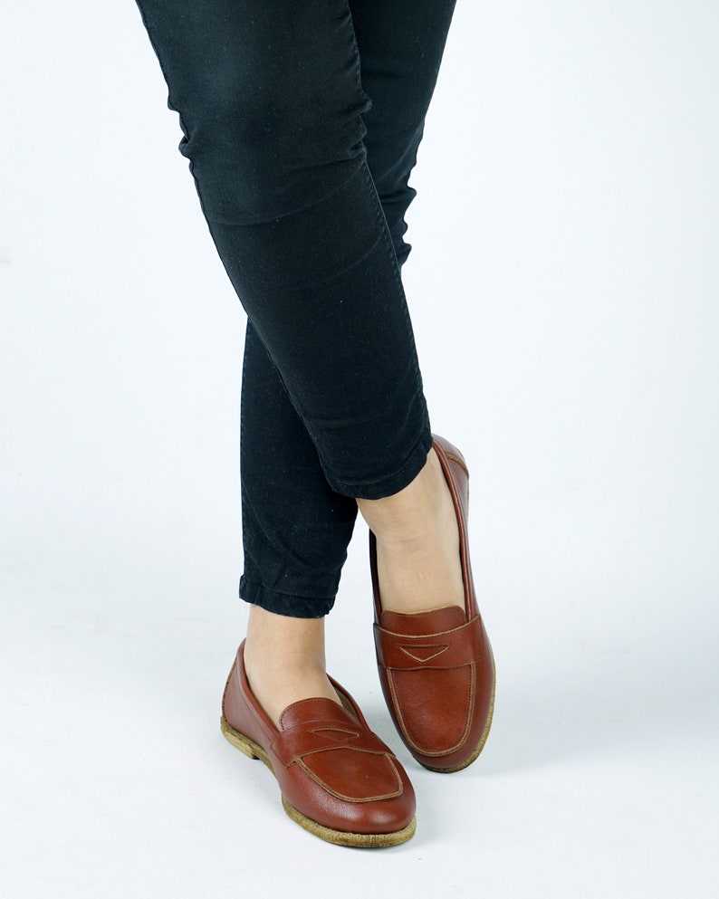 May include: A pair of brown leather loafers with a simple design. The loafers have a pointed toe and a low heel.