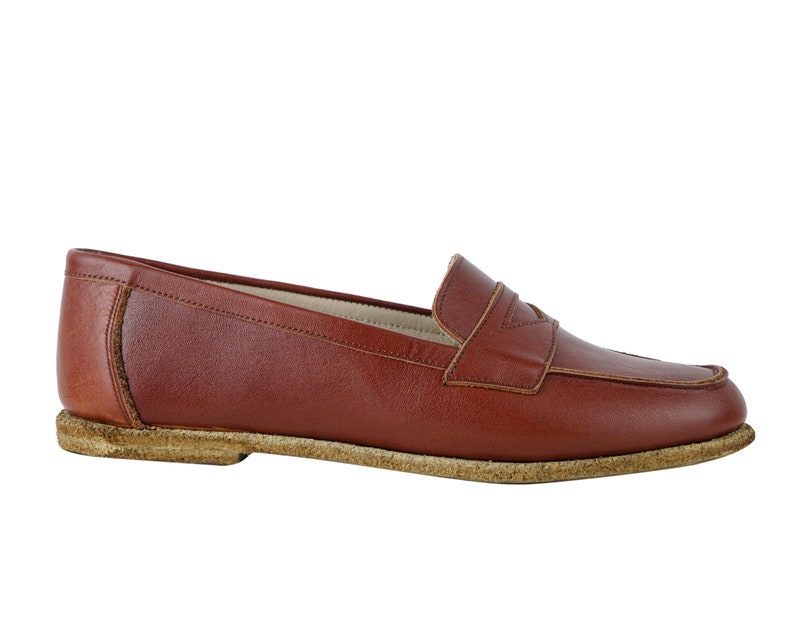 May include: A pair of brown leather loafers with a simple design. The loafers have a rounded toe and a low heel.