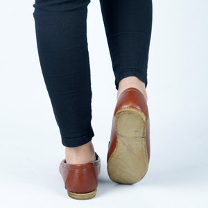 May include: A pair of brown leather loafers with a slightly pointed toe. The shoes are worn and have a worn leather look.