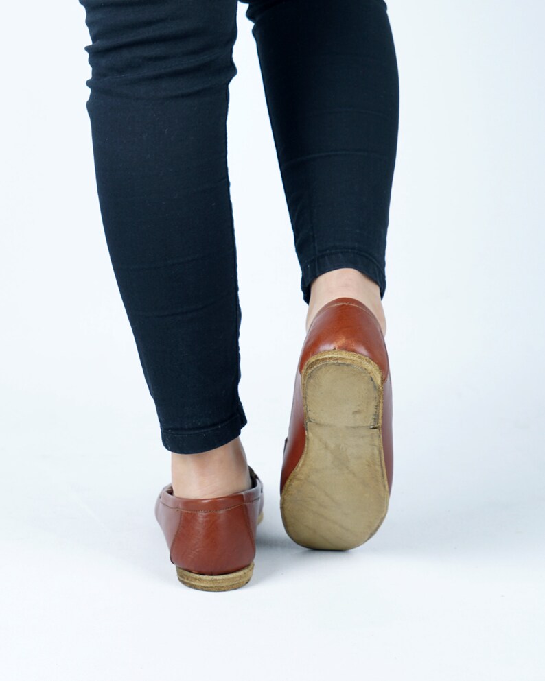 May include: A pair of brown leather loafers with a slightly pointed toe. The shoes are worn and have a worn leather look.