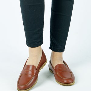 May include: A pair of brown leather loafers with a simple design. The loafers have a rounded toe and a low heel.