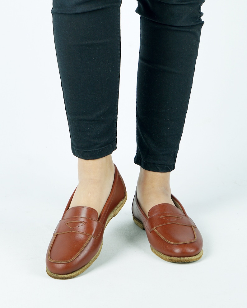 May include: A pair of brown leather loafers with a simple design. The loafers have a rounded toe and a low heel.