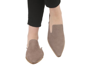 May include: A pair of light brown suede slip-on shoes with pointed toes.