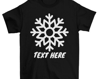 Op de afbeelding: Zwart T-shirt met een wit sneeuwvlokontwerp en de tekst "TEXT HERE" gedrukt op de voorkant.