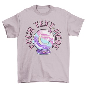 May include: A lavender t-shirt with a pink, blue, and purple swirling crystal ball graphic. The text "YOUR TEXT HERE" surrounds the crystal ball.