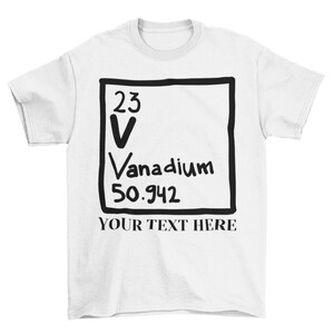 May include: White t-shirt with a black and white graphic of the periodic table element Vanadium. The graphic includes the atomic number 23, the symbol V, the name Vanadium, and the atomic weight 50.942. The text "YOUR TEXT HERE" is printed below the graphic.