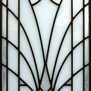 May include: A rectangular window with a black metal frame and a white, fan-shaped design. The design is composed of curved and straight lines, with frosted glass accents on the sides. The window has a classic, Art Deco style.