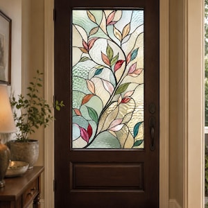 Op de afbeelding: Een donkerbruine houten deur met een groot rechthoekig glas-in-lood raam. Het glas toont een vloeiend botanisch patroon van bladeren in tinten roze, groen en blauwgroen, tegen een gestructureerde, halfdoorzichtige achtergrond.
