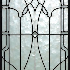 May include: A rectangular stained glass window with a black metal frame. The design features a symmetrical pattern of black lines and clear, textured glass. The glass has a cloudy, marbled appearance, and the overall effect is elegant and decorative.