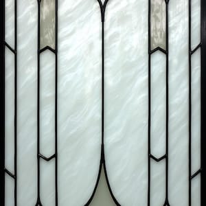May include: Stained glass window with a black metal frame. The glass is white with a cloudy pattern, and the design includes geometric shapes and lines. The window has a classic, elegant style.