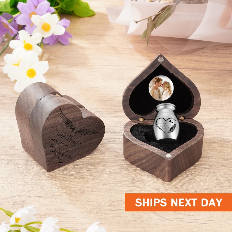 May include: Heart-shaped wooden urns, one closed and one open, displaying a small silver urn inside. The open urn has a photo and the words "Forever in my heart." The closed urn has the text "Your wings were ready but my heart was not."