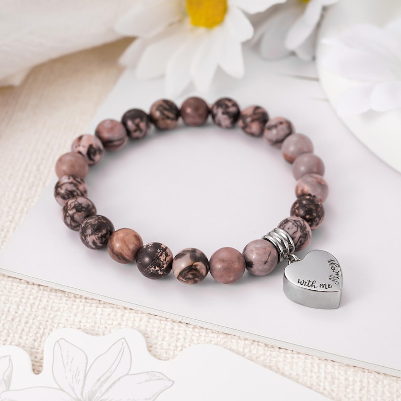 May include: A brown and pink beaded bracelet with a silver heart charm that says "Always with me".