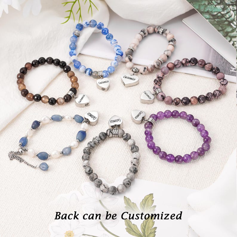 May include: Seven bracelets with heart charms, each with a different color and pattern of beads. The charms are engraved with the word "Customized". Back can be Customized.