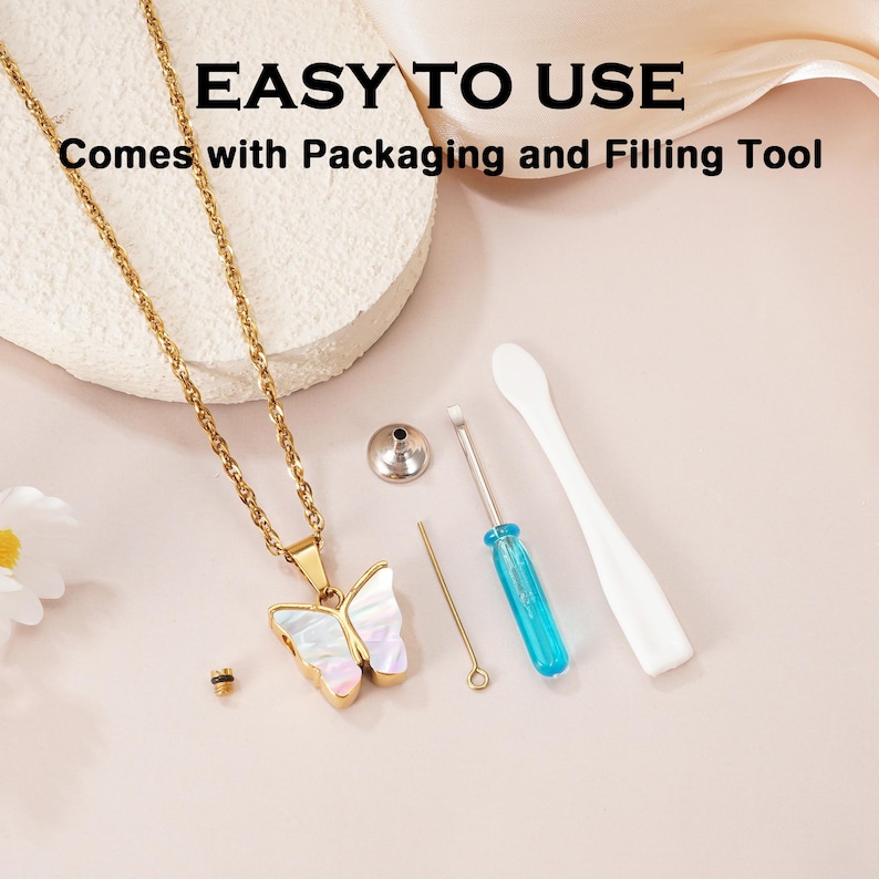 May include: A gold-tone chain necklace with a butterfly pendant featuring an iridescent inlay. The set includes a small metal funnel, a thin metal pin, a screwdriver with a blue handle, and a white plastic spatula. Text reads: EASY TO USE.