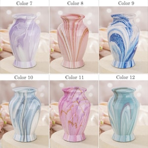 May include: A collection of six small urns with lids, each featuring a unique marbled finish. The colors include lavender, pink with gold veins, blue and white swirls, grey and white patterns, magenta with gold veins, and teal with white swirls.