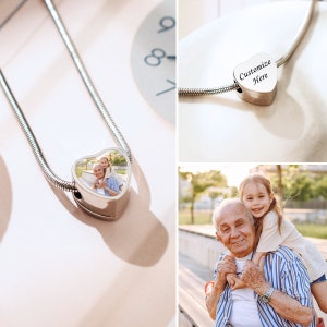 May include: A silver chain necklace with a heart-shaped charm. The charm has a photo of an older man and a young girl. The charm also has the text "Customize Here" engraved on it.