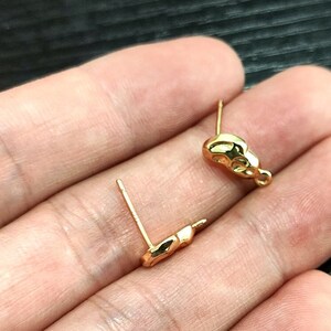 May include: Two gold-toned earring findings with a loop on one end and a post on the other end.