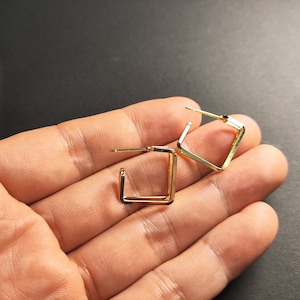 Puede incluir: Un par de pendientes de aro cuadrados de oro. Los pendientes son simples y elegantes, y serían una gran adición a cualquier colección de joyas.