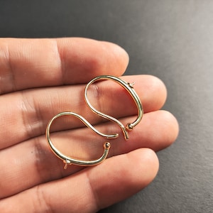 May include: Two gold-toned earring hooks with a small ball at the end of each hook.