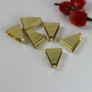 May include: Six gold-colored triangle-shaped metal pendant bails. The bails have a smooth, shiny finish.