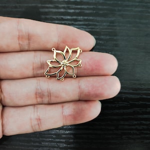 May include: Gold-toned metal flower charm with a detailed design and five loops for attaching jewelry findings.