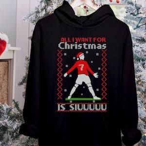 May include: Black hoodie with a red and white Christmas design featuring a soccer player and the text "All I want for Christmas is Siuuuuuu".
