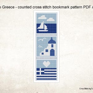 May include: A cross-stitch bookmark pattern with three blue and white images. The top image shows a sailboat on the sea, the middle image shows a church, and the bottom image shows the Greek flag and a heart. Text at the top reads "Hello Greece".