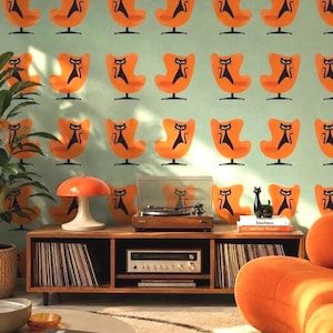 Pode incluir: Um móvel multimédia de madeira contém um gira-discos, um recetor prateado e discos de vinil. Um candeeiro em forma de cogumelo e uma estatueta de gato preto estão em cima. A parede tem papel de parede com um padrão de cadeiras cor de laranja.