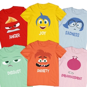 May include: Six t-shirts featuring characters from the movie Inside Out. The shirts are red, yellow, light blue, light green, orange, and pink. Each shirt has a different character's face on it, with the character's name printed below the face. The characters are Anger, Joy, Sadness, Disgust, Anxiety, and Embarrassment.